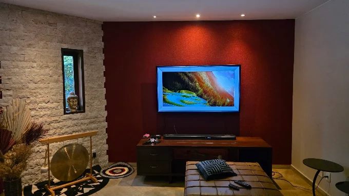 Suporte fixo com TV e home theater instalados em sala de estar em Brasília