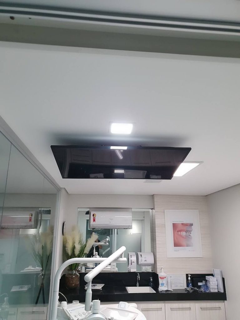 TV instalada em suporte de teto sobre a cadeira de consultório odontológico em Brasília